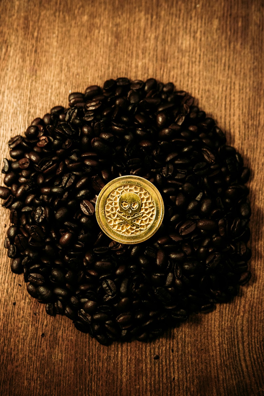 coffee beans with a gold emblem in the middle decorated with a skull etching